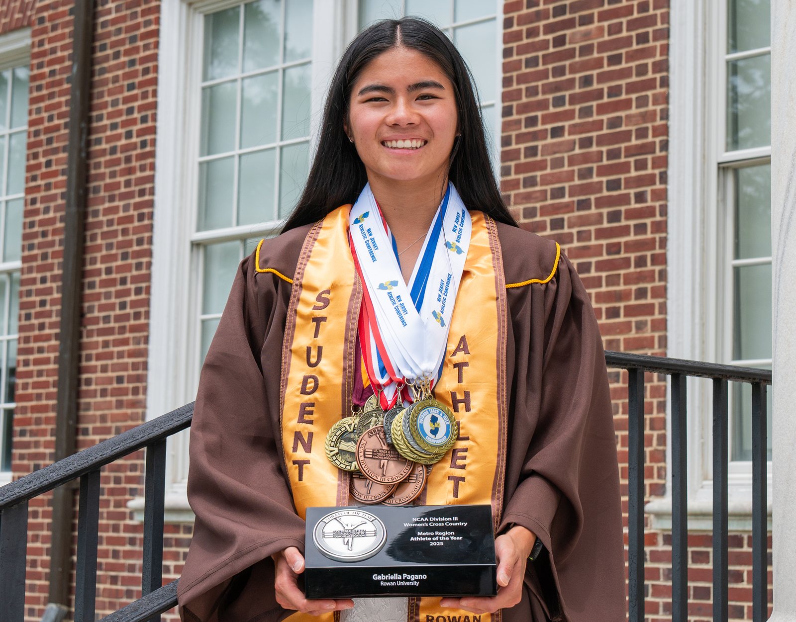 Gabriella in a Rowan student-athlete stole, holding her medals and award